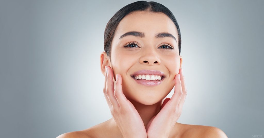 Woman smiling with her hands on her face (MODEL)